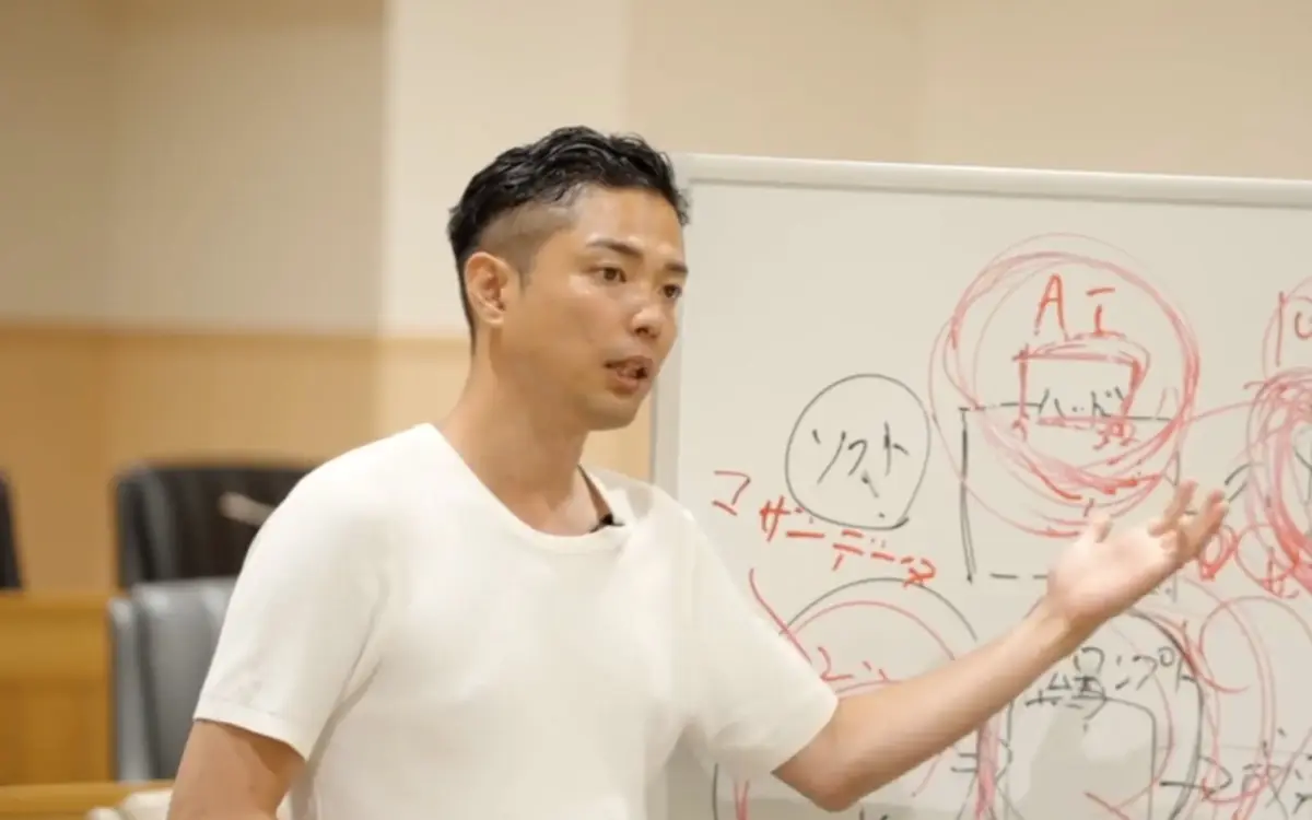 合宿の講義で、書き込んだ白板の前で話す白石達也